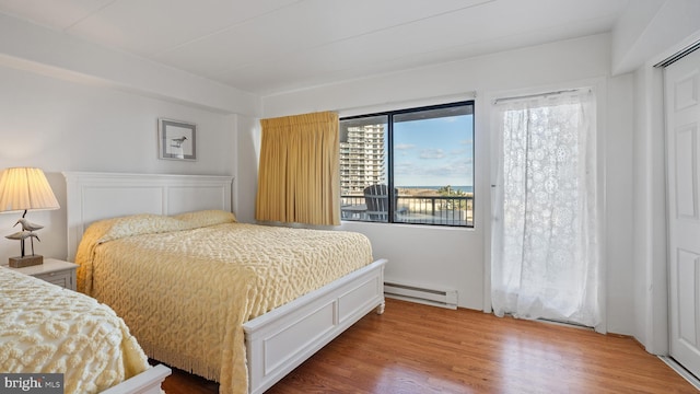 bedroom featuring hardwood / wood-style flooring and a baseboard heating unit