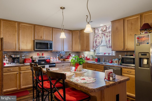 kitchen featuring pendant lighting, a center island, sink, a breakfast bar area, and stainless steel appliances