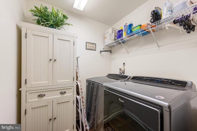 laundry room featuring washer and clothes dryer and cabinets