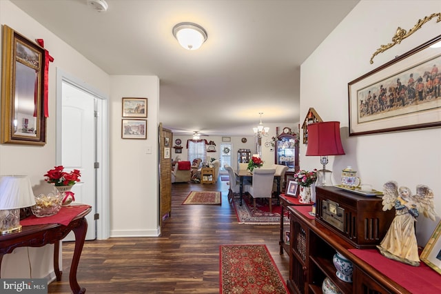 hallway with dark wood-type flooring and a chandelier