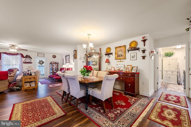 dining space featuring dark wood-type flooring and ceiling fan with notable chandelier