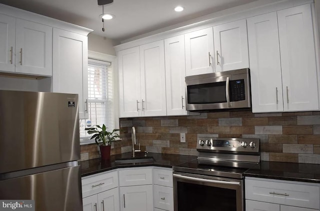 kitchen with decorative backsplash, sink, white cabinets, and appliances with stainless steel finishes