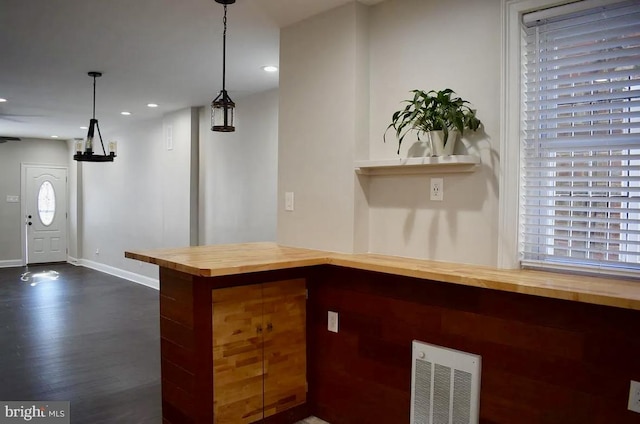 bar featuring wood counters, pendant lighting, and dark hardwood / wood-style flooring