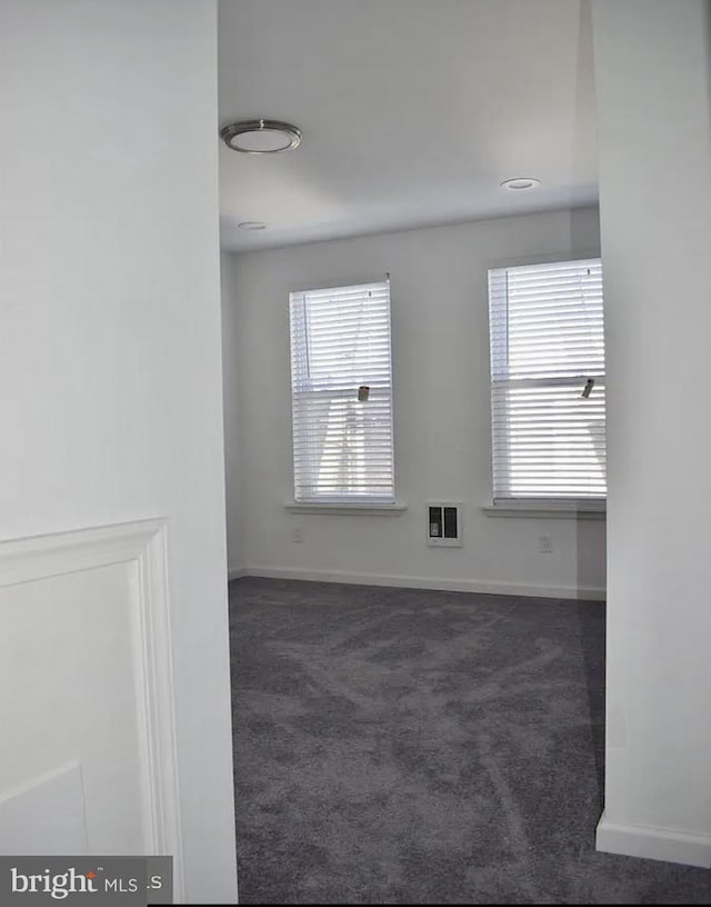 carpeted spare room featuring heating unit and a healthy amount of sunlight