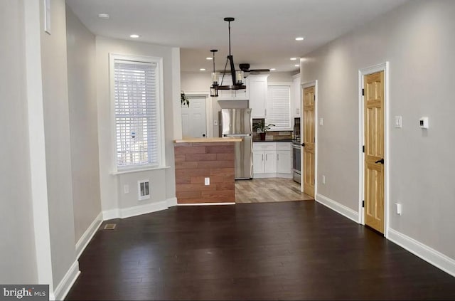 kitchen with pendant lighting, dark wood-type flooring, butcher block countertops, white cabinetry, and stainless steel appliances