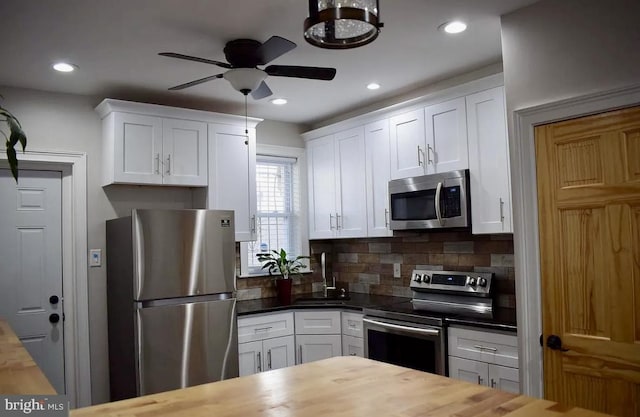 kitchen featuring white cabinetry, stainless steel appliances, and wooden counters