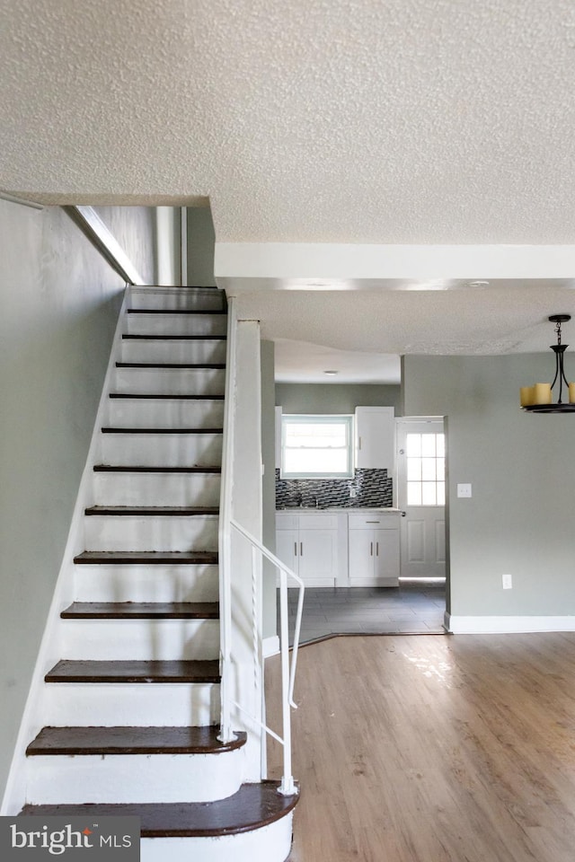 staircase featuring wood-type flooring and a textured ceiling