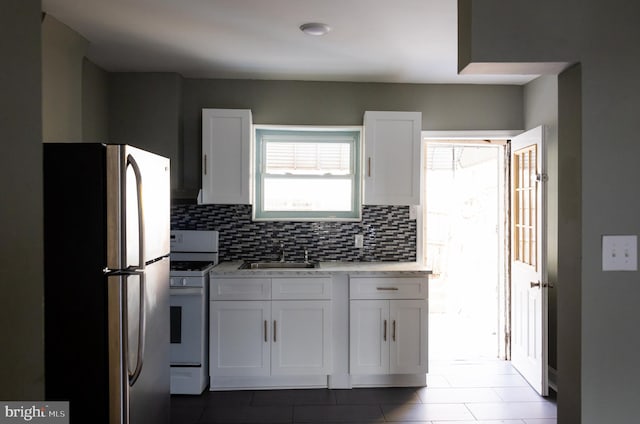 kitchen featuring white cabinets, stainless steel fridge, sink, and white stove