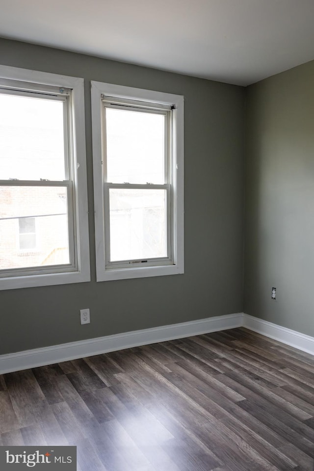 empty room featuring dark hardwood / wood-style flooring and a wealth of natural light