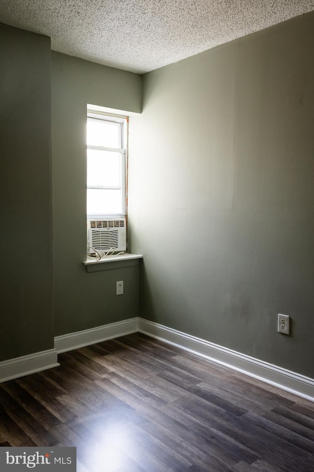 unfurnished room featuring dark hardwood / wood-style floors, cooling unit, and a textured ceiling