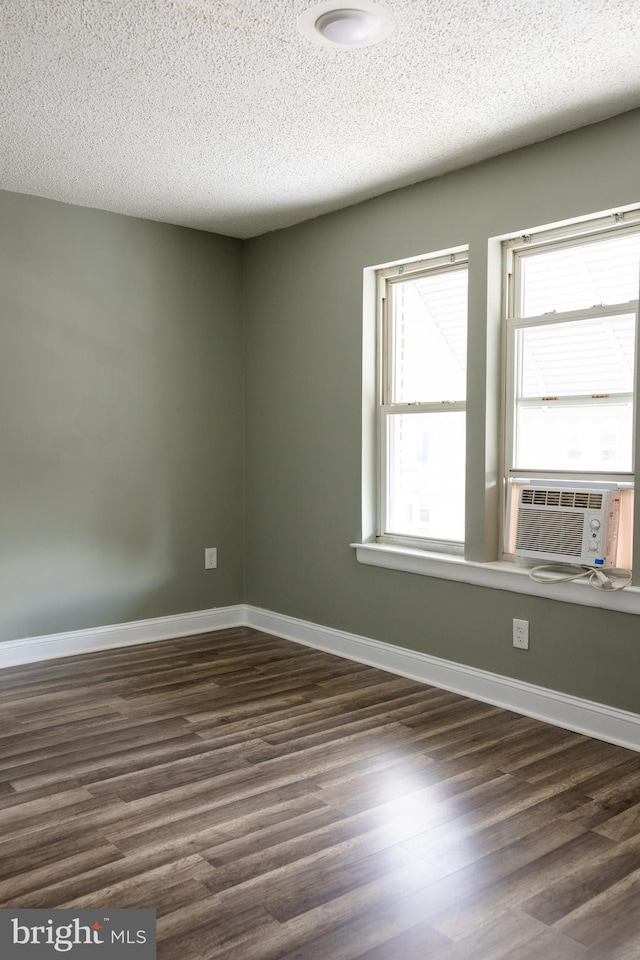 spare room with a textured ceiling, cooling unit, and dark wood-type flooring