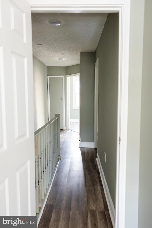 hallway featuring a textured ceiling and dark hardwood / wood-style floors