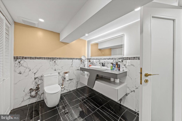 bathroom featuring sink, tile walls, and toilet