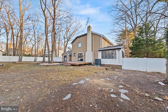 rear view of house featuring central air condition unit, a wooden deck, and a sunroom