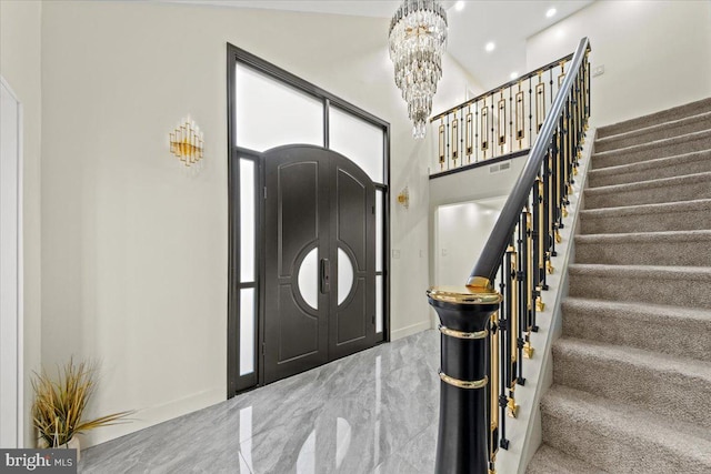 foyer with high vaulted ceiling, light colored carpet, and an inviting chandelier