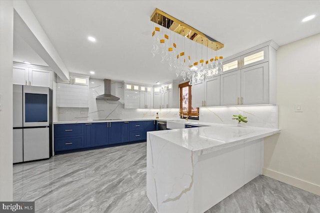 kitchen featuring wall chimney exhaust hood, white cabinetry, blue cabinetry, and built in refrigerator