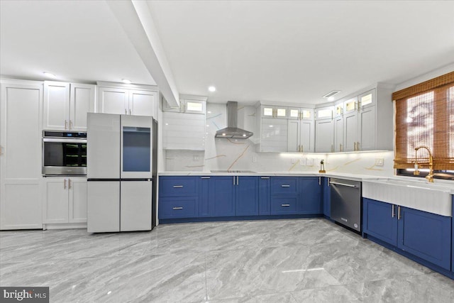 kitchen featuring white cabinets, sink, wall chimney exhaust hood, decorative backsplash, and appliances with stainless steel finishes