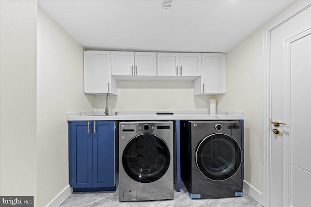 clothes washing area featuring washer and clothes dryer, cabinets, and sink