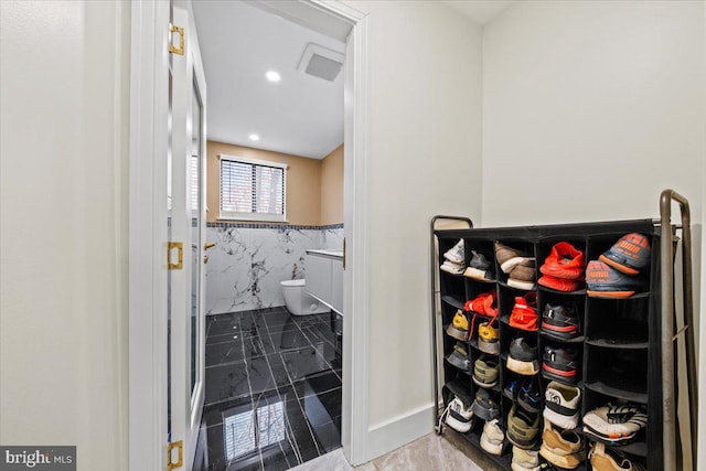 bathroom featuring tile patterned floors, vanity, toilet, and tile walls