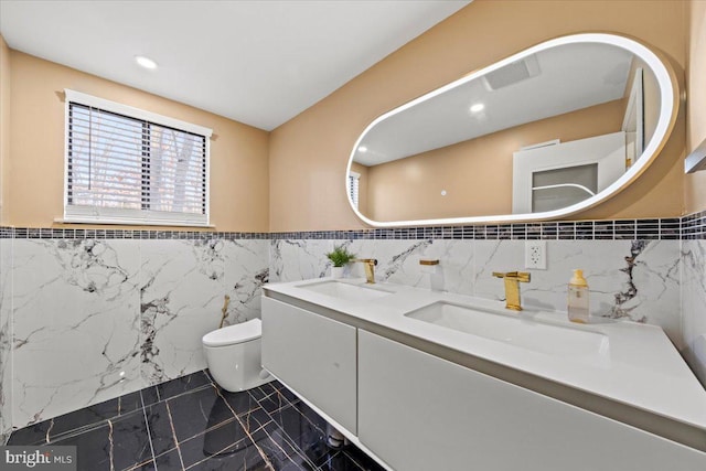 bathroom with vanity, toilet, and tile walls