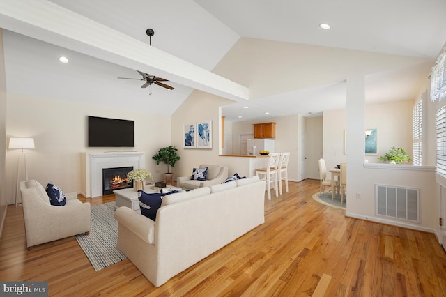 living room with lofted ceiling with beams, ceiling fan, and light hardwood / wood-style flooring