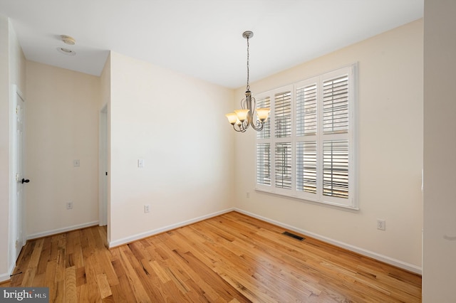 spare room featuring a chandelier and hardwood / wood-style flooring