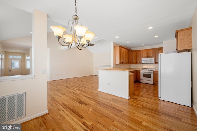 kitchen featuring light hardwood / wood-style floors, white appliances, kitchen peninsula, and an inviting chandelier