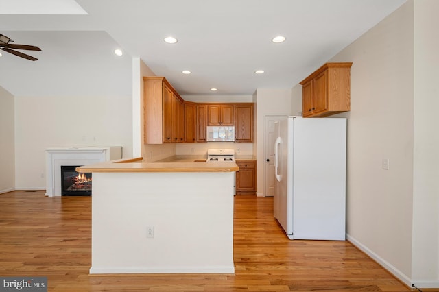 kitchen with kitchen peninsula, light wood-type flooring, white appliances, and ceiling fan