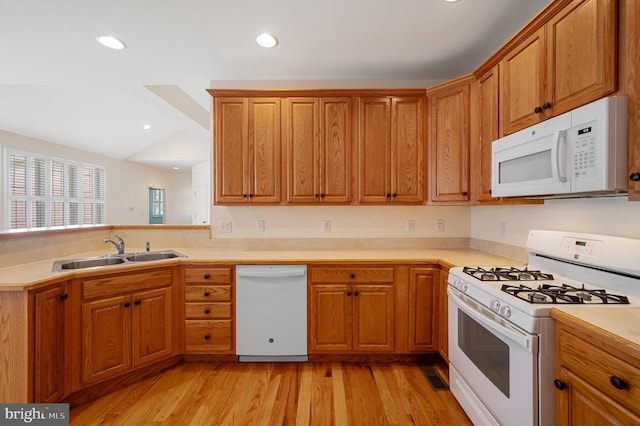 kitchen with kitchen peninsula, sink, light hardwood / wood-style floors, and white appliances