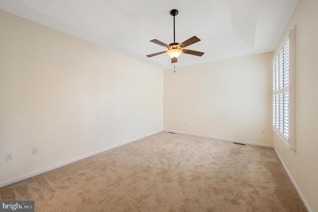 unfurnished room featuring light colored carpet, a raised ceiling, and ceiling fan