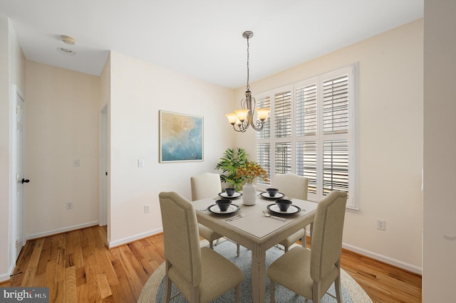 dining area with an inviting chandelier and light hardwood / wood-style flooring