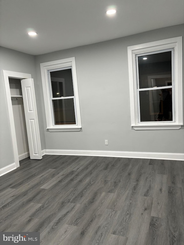 unfurnished bedroom with dark wood-type flooring and a closet