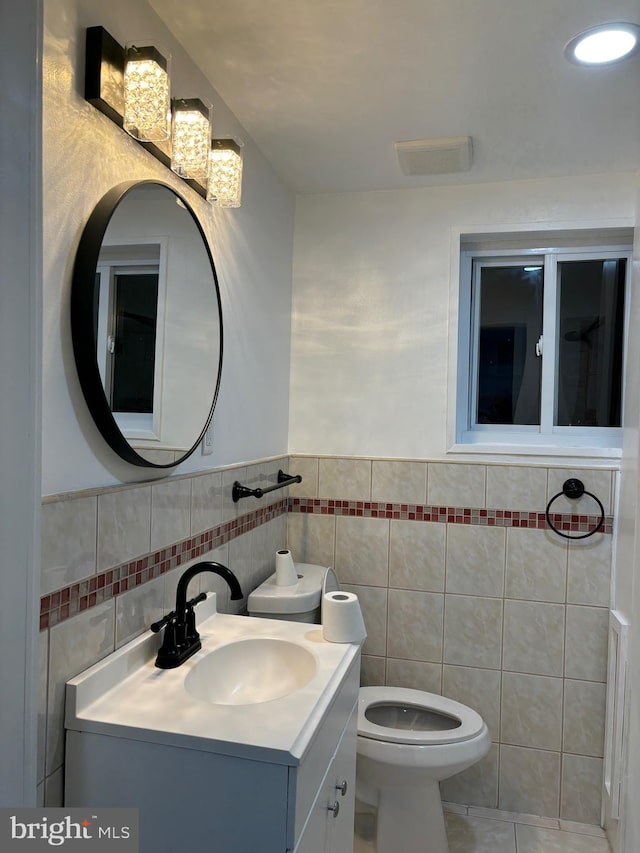 bathroom featuring tile patterned floors, vanity, toilet, and tile walls