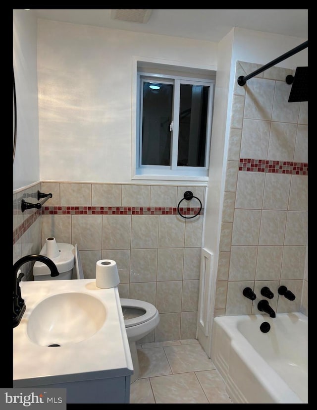 full bathroom with tile patterned floors, toilet, tiled shower / bath, tile walls, and vanity