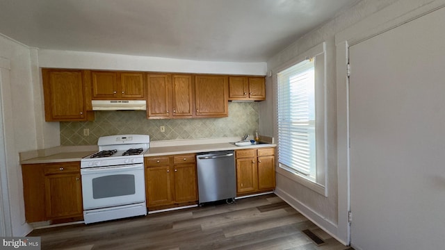 kitchen featuring dark wood-type flooring, white gas stove, stainless steel dishwasher, and sink