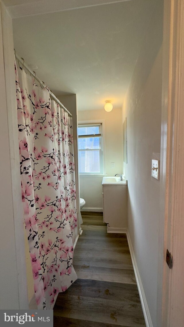 bathroom featuring vanity, hardwood / wood-style flooring, toilet, and curtained shower