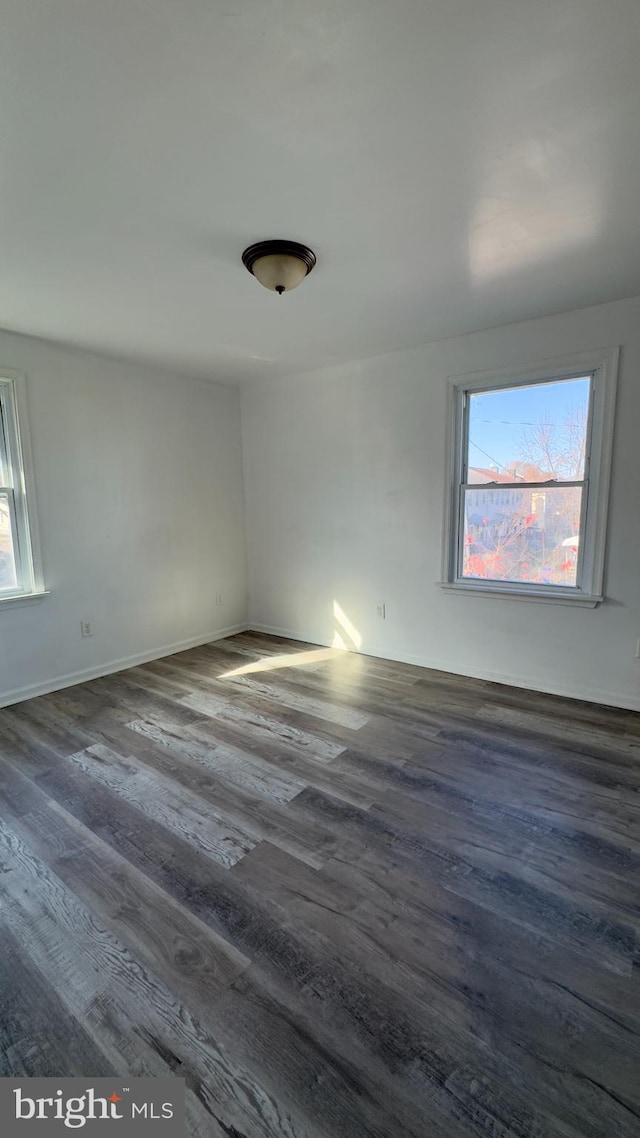 unfurnished room featuring a wealth of natural light and dark wood-type flooring