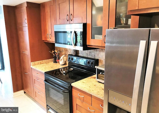 kitchen featuring light stone counters, tasteful backsplash, appliances with stainless steel finishes, and brown cabinetry