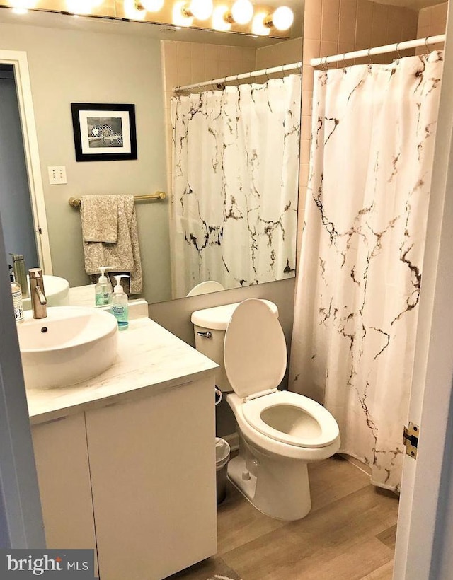 bathroom with a shower with shower curtain, toilet, wood finished floors, and vanity