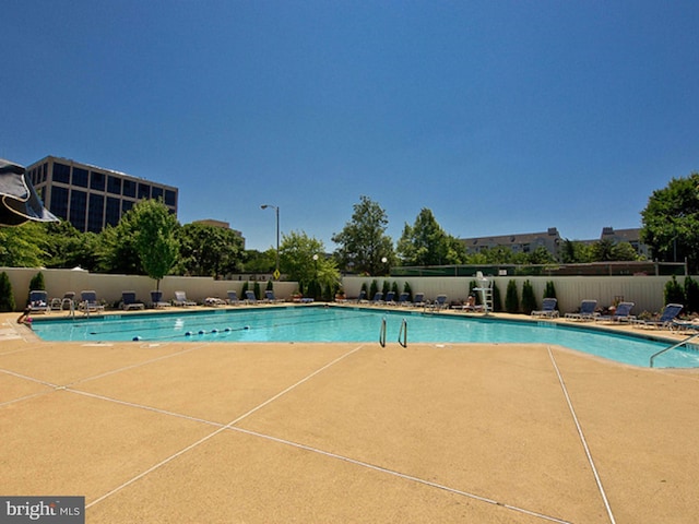 community pool with a patio area and fence