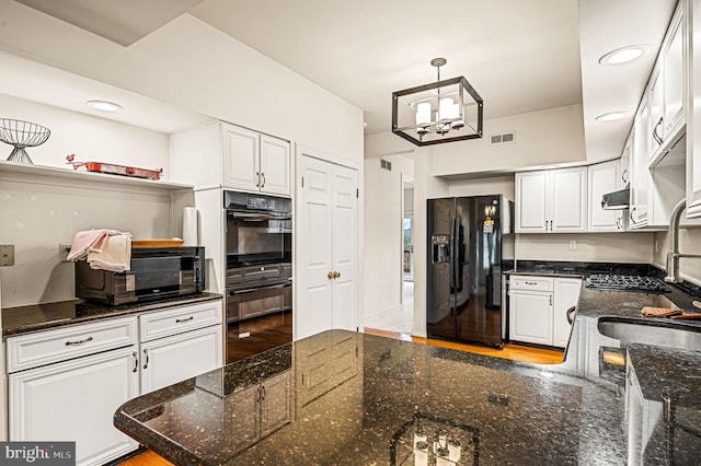 kitchen with pendant lighting, white cabinetry, dark stone counters, and black appliances