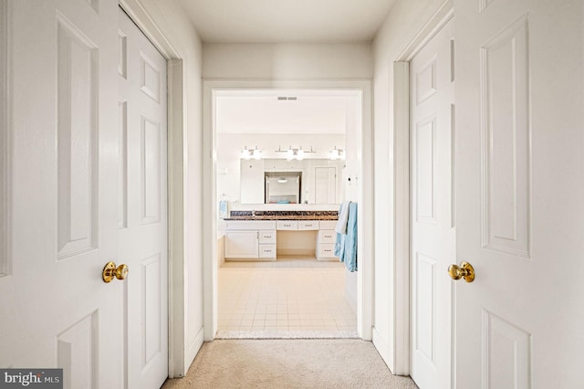 corridor featuring light colored carpet and sink