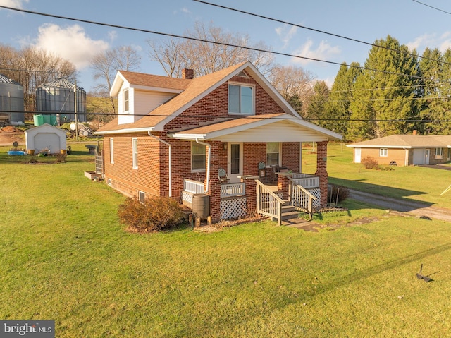 view of front facade with covered porch, an outdoor structure, and a front lawn