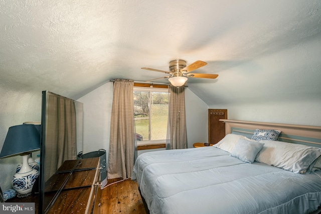 bedroom with a textured ceiling, ceiling fan, dark hardwood / wood-style flooring, and vaulted ceiling