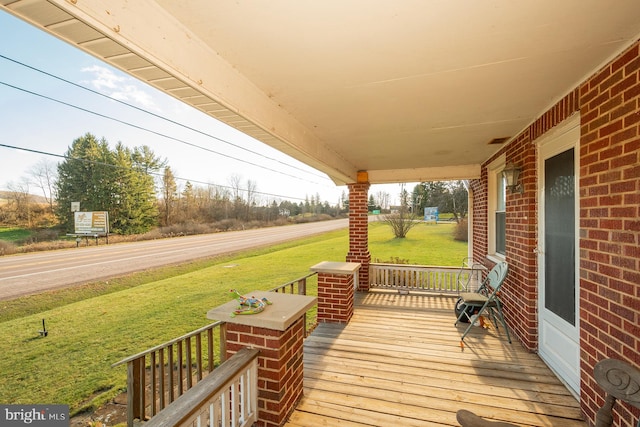 wooden terrace with a lawn and covered porch