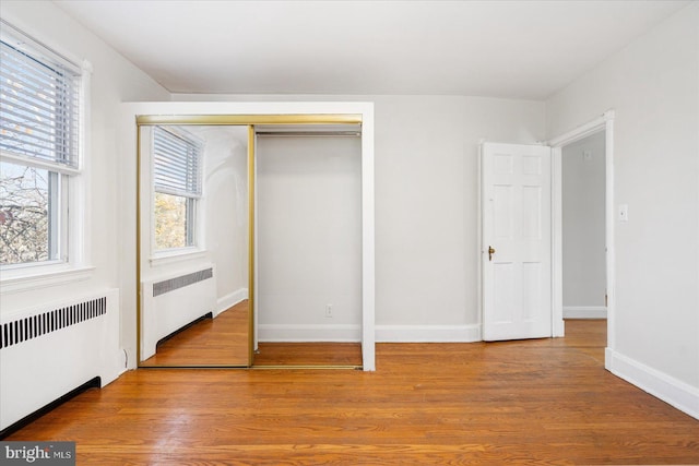 841 E Belvedere Ave E, Baltimore, MD 21212 - unfurnished bedroom with radiator, wood finished floors, and multiple windows