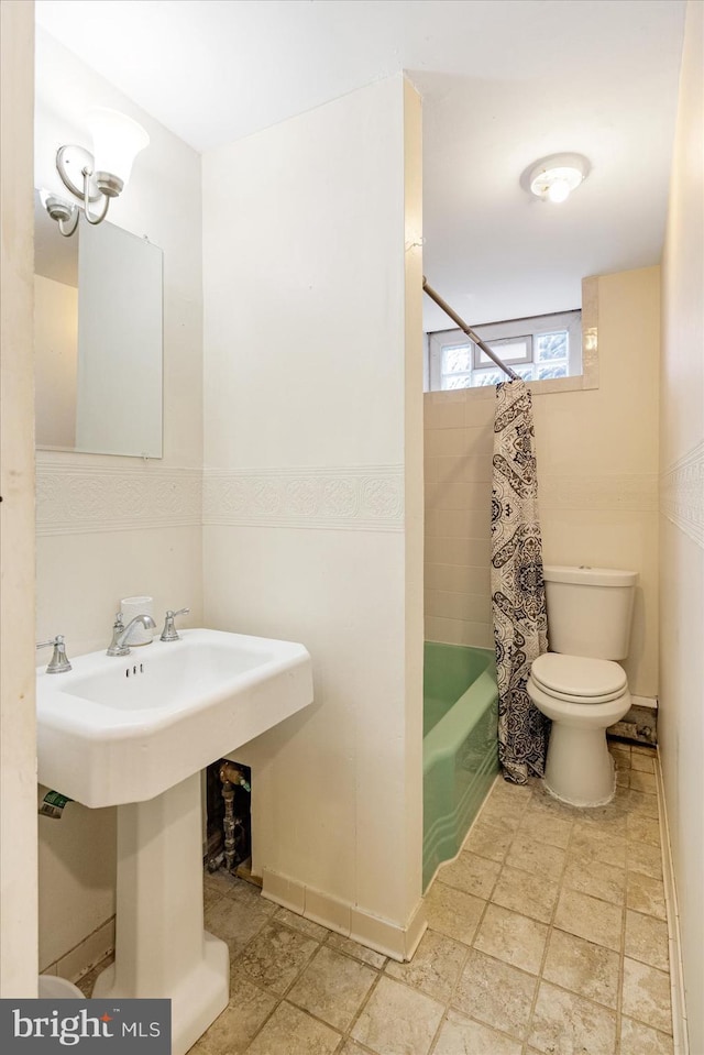 841 E Belvedere Ave E, Baltimore, MD 21212 - full bath featuring toilet, stone tile floors, shower / bathtub combination with curtain, a sink, and baseboards