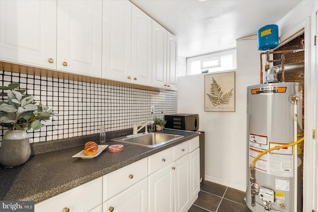 841 E Belvedere Ave E, Baltimore, MD 21212 - kitchen featuring gas water heater, a sink, black microwave, tasteful backsplash, and white cabinetry