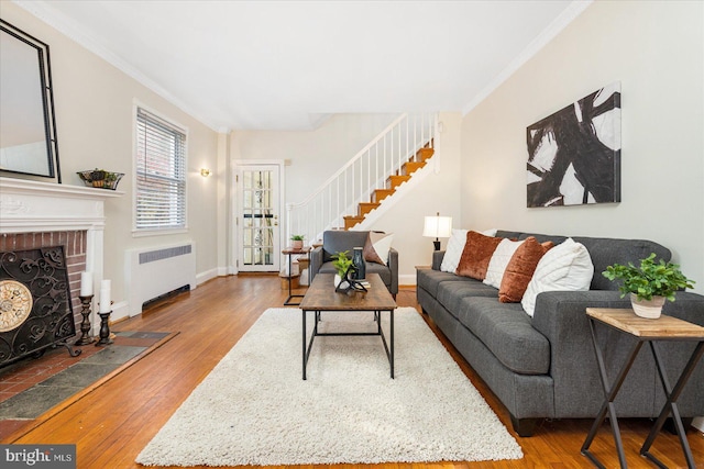 841 E Belvedere Ave E, Baltimore, MD 21212 - living room with radiator, wood finished floors, stairs, ornamental molding, and a brick fireplace
