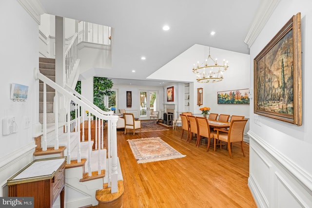 entryway featuring vaulted ceiling, wood-type flooring, crown molding, and a chandelier